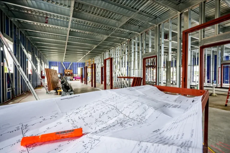 Construction drawings spread out with a highlighter inside a building under construction