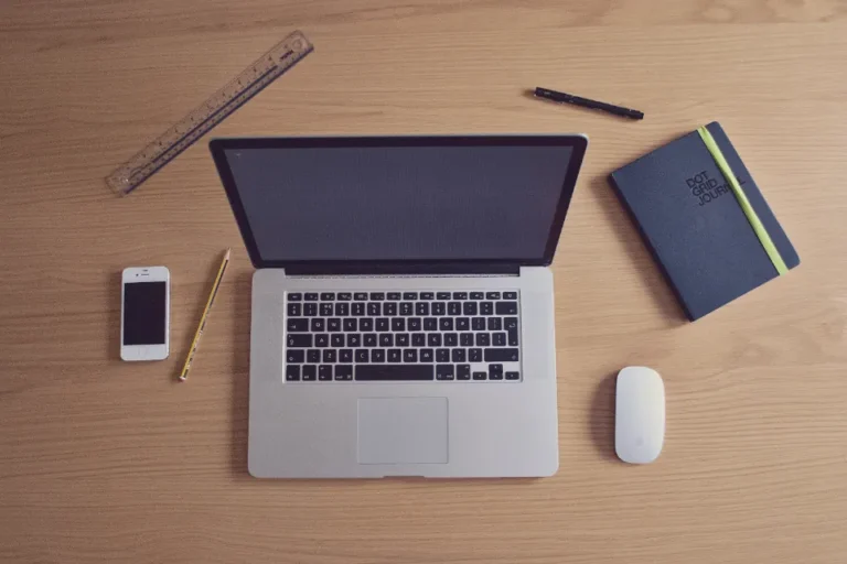 Overhead view of a desk with a laptop, notebook, ruler and pencil