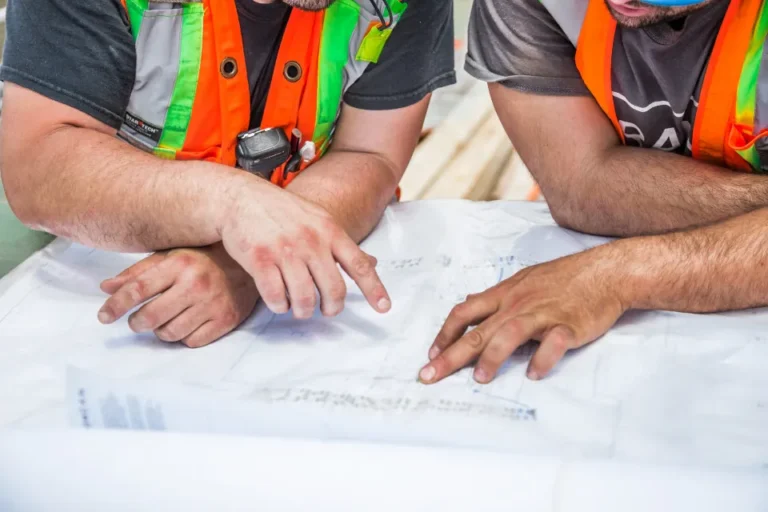 Construction team in high-visibility vests reviewing drawings on a table