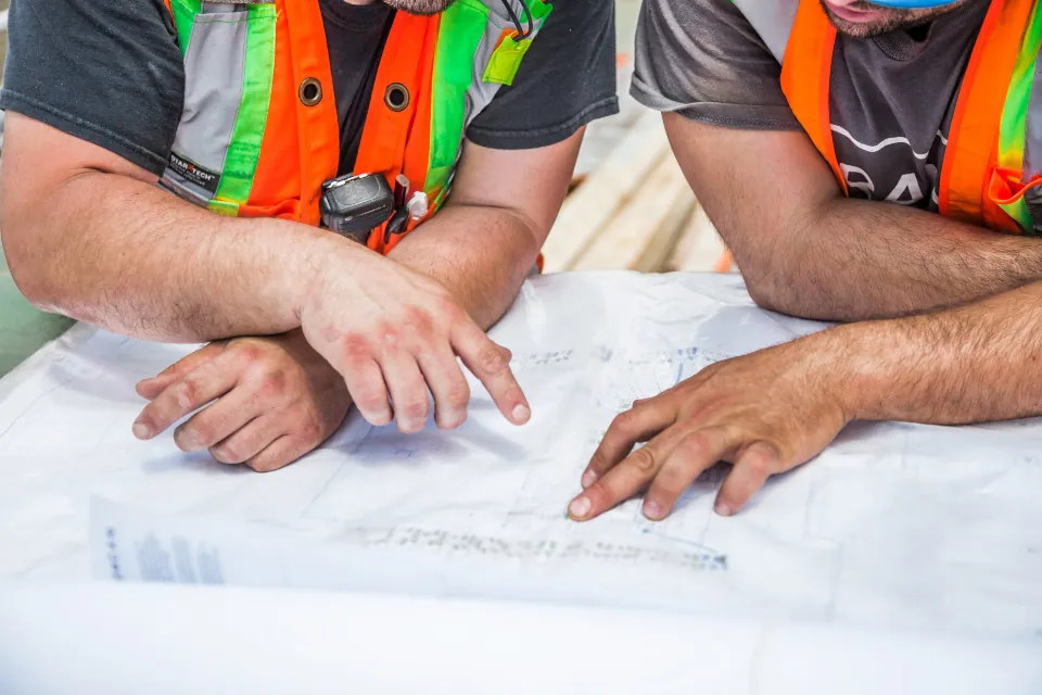 Construction team in high-visibility vests reviewing drawings on a table