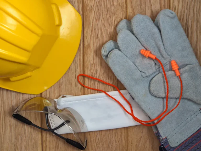 Hard hat, work gloves and rolled drawings on a workbench