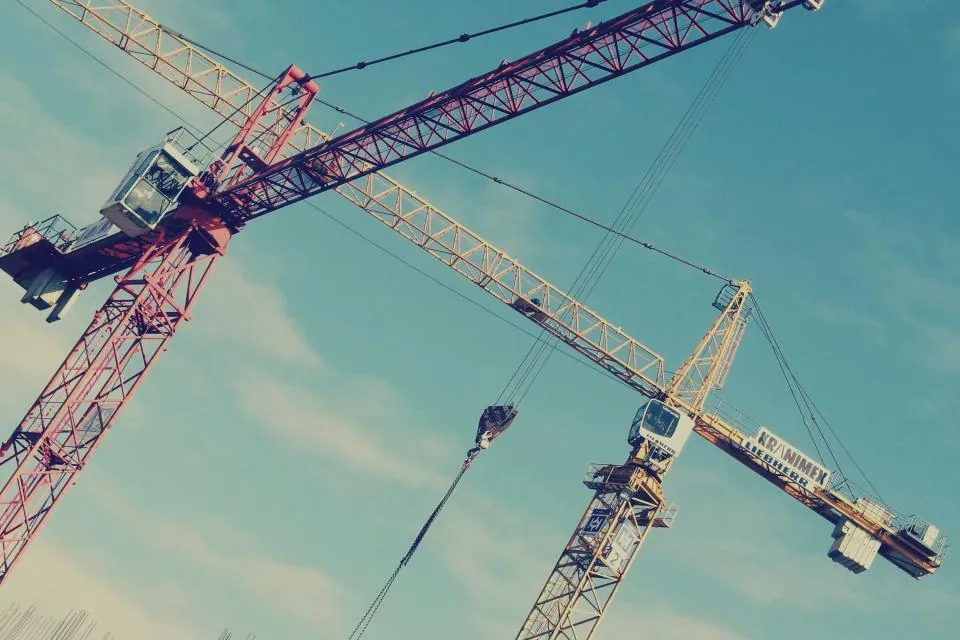Tower cranes against an open sky above a building site