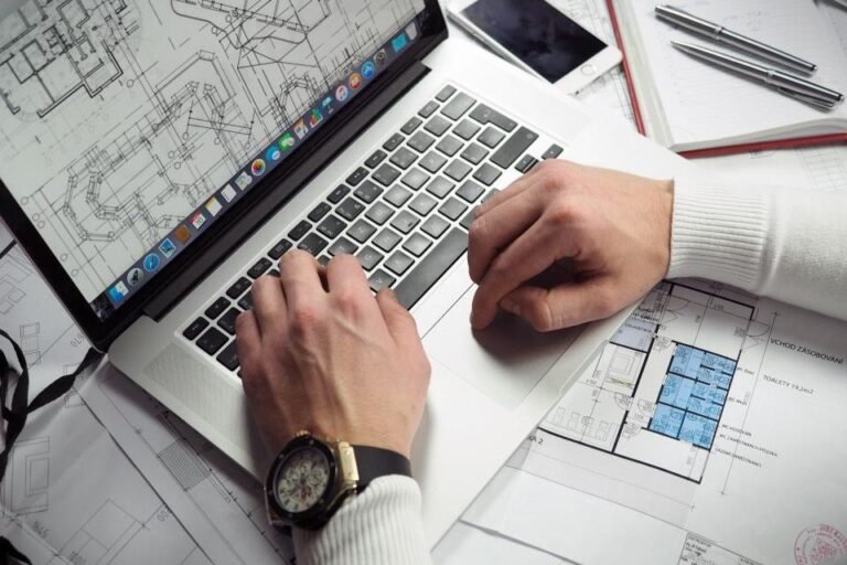 Laptop and notebook resting on construction blueprints during a takeoff