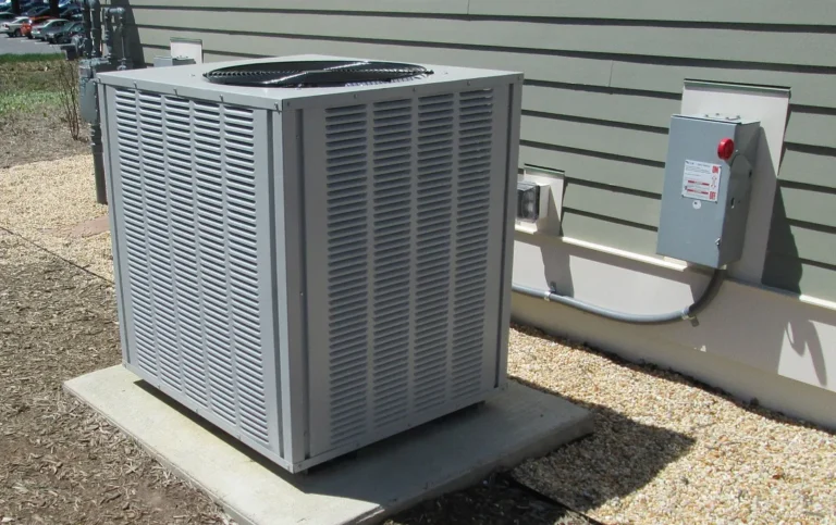 Residential air conditioning condenser unit on a concrete pad beside a house
